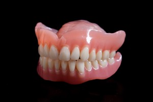 Acrylic denture prosthesis of the upper and lower jaws of a man close-up on a black background